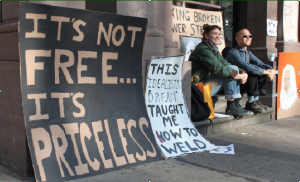 A large collection of signs advocating Cooper Union’s tuition-free mission accumulate on the steps of the Foundation Building on December 3. (Henry Miller)