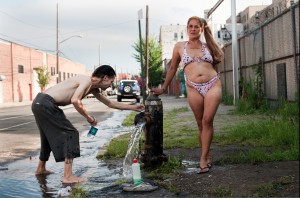 Arnade’s photograph of two subjects, Michael and Sunshine, bathing by a fire hydrant in the streets of Hunts Point. Photo by Chris Arnade