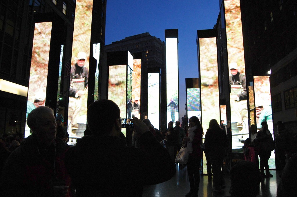 Fans walk through pillars of screens, which play clips of NFL history. 