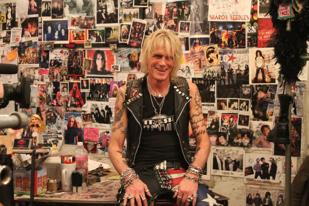 Local punk legend and owner of Trash & Vaudeville, Jimmy, sits in front of their wall of famous customers.
