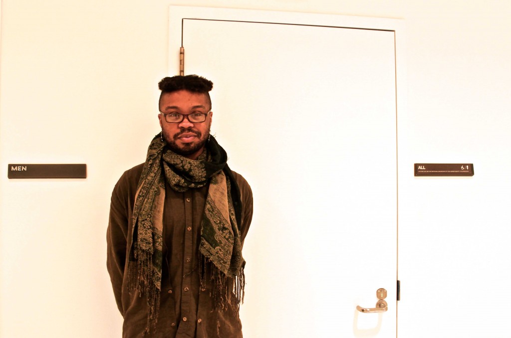 Khon Su, a member of the committee responsible for the all-gender bathrooms inclusion on campus, standing between the men's room and the all-gender bathroom in the University Center. Photo by: Shea Carmen Swan