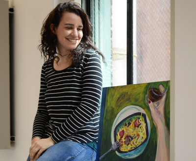 Kate Saubestre with two of her paintings. Photo by Kianna Stupakoff.