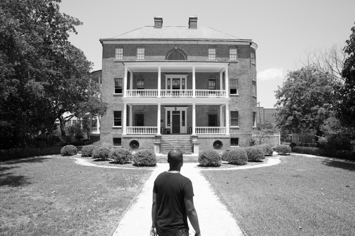 The back of Jermaine Manigault looking at a large former-plantation house.