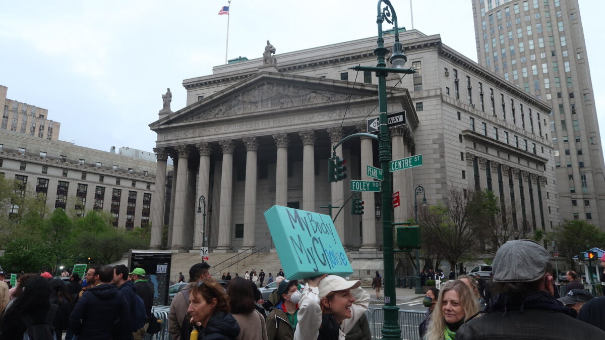 A woman holds up a sign reading “my body my choice” across the road from the New York State Supreme Court.