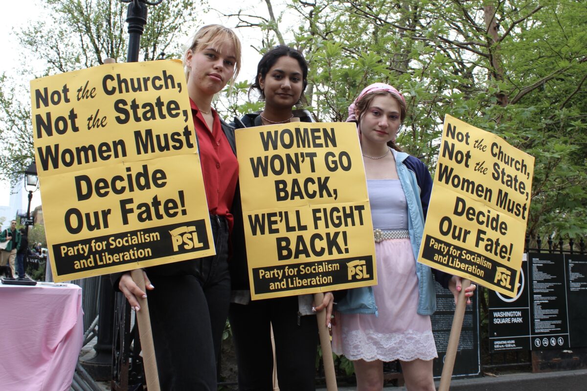 Three college students holding signs that say “Not the Church, not the State, Women must decide our fate” and “women won’t go back, we’ll fight back!”