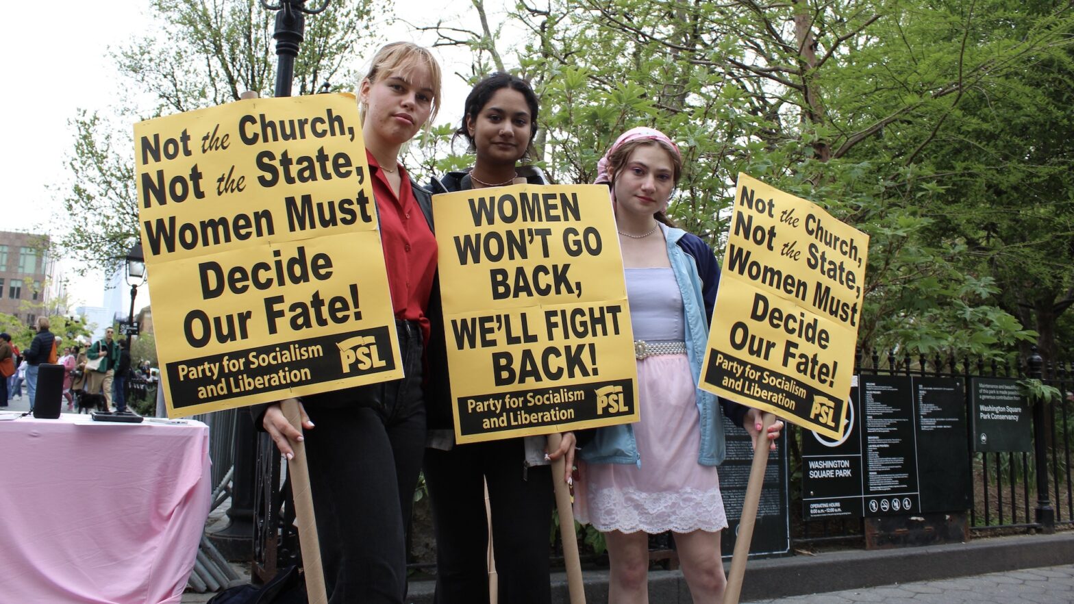 Three college-aged students holding signs that say “Not the Church, not the State, Women must decide our fate” and “women won’t go back, we’ll fight back!”