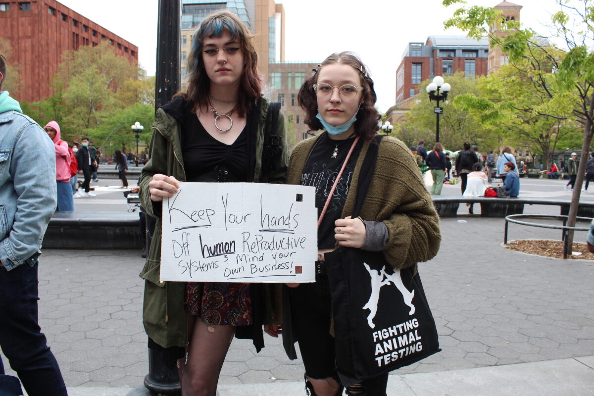 Two protesters hold up a sign reading “Keep your hands off human reproductive systems. Mind your own business!”