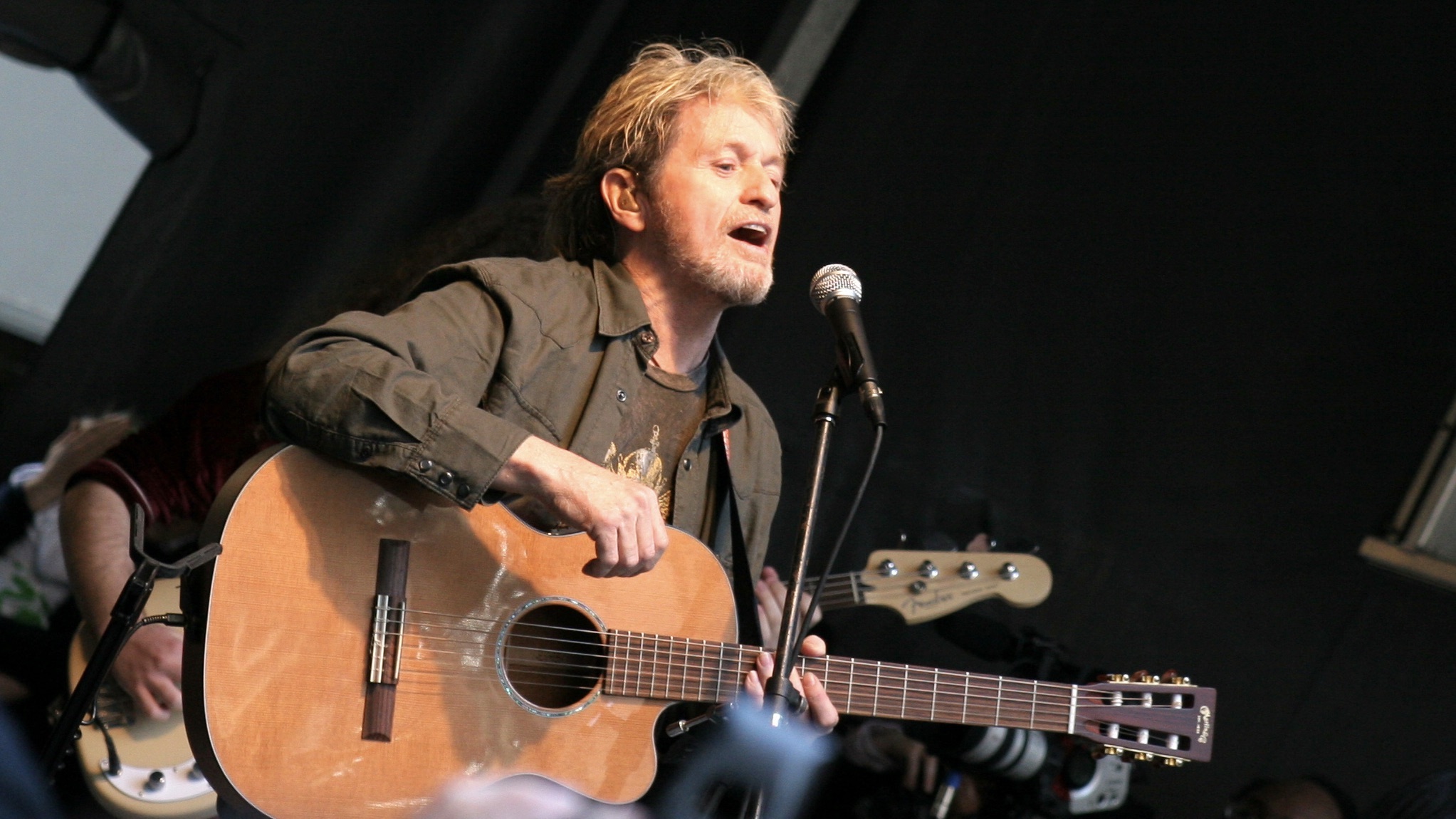 Jon Anderson sings and plays guitar on stage.