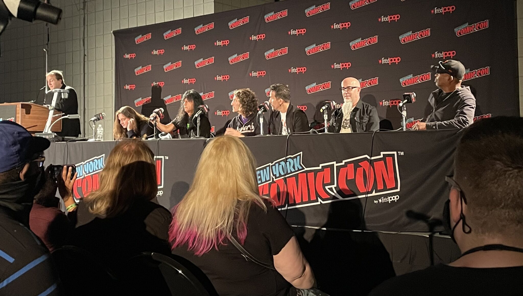 Anthrax and Chuck D sitting at a table at New York Comic Con discussing comics.