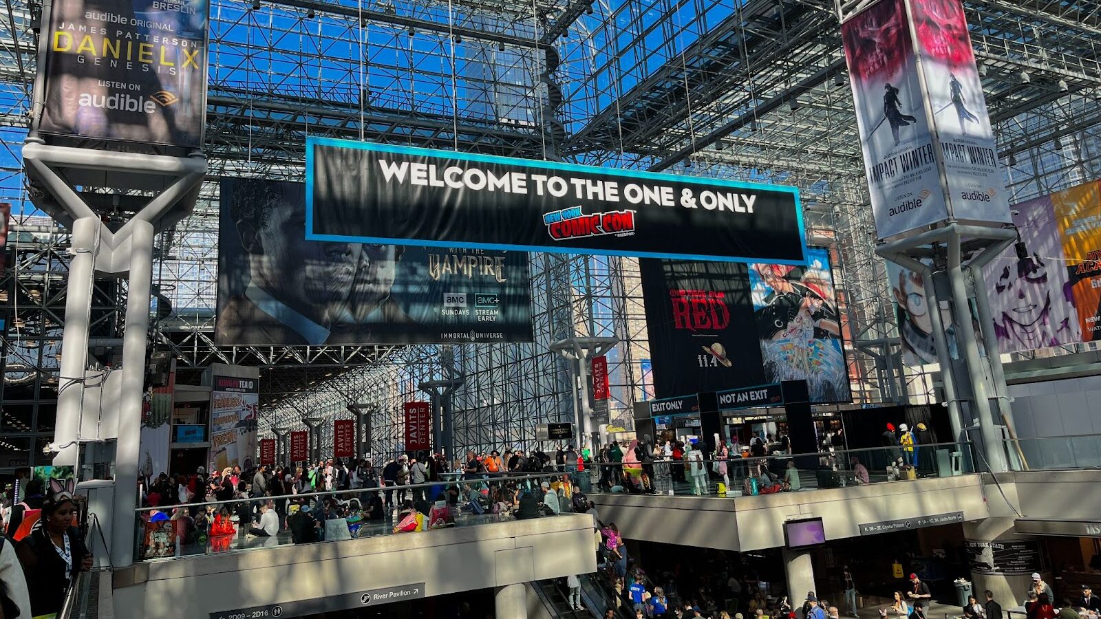 A crowd gathers at New York Comic Con at the Jacob Javits Center with a banner hanging that reads "The one and only"