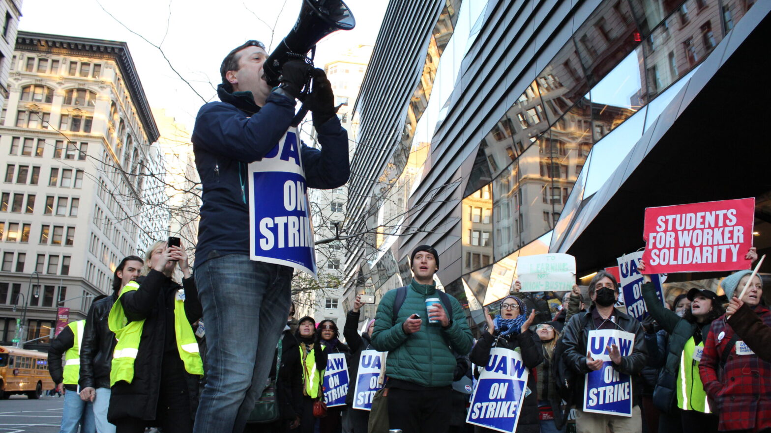 Photo of New School part-time faculty and students protesting outside the University Center with a bullhorn.