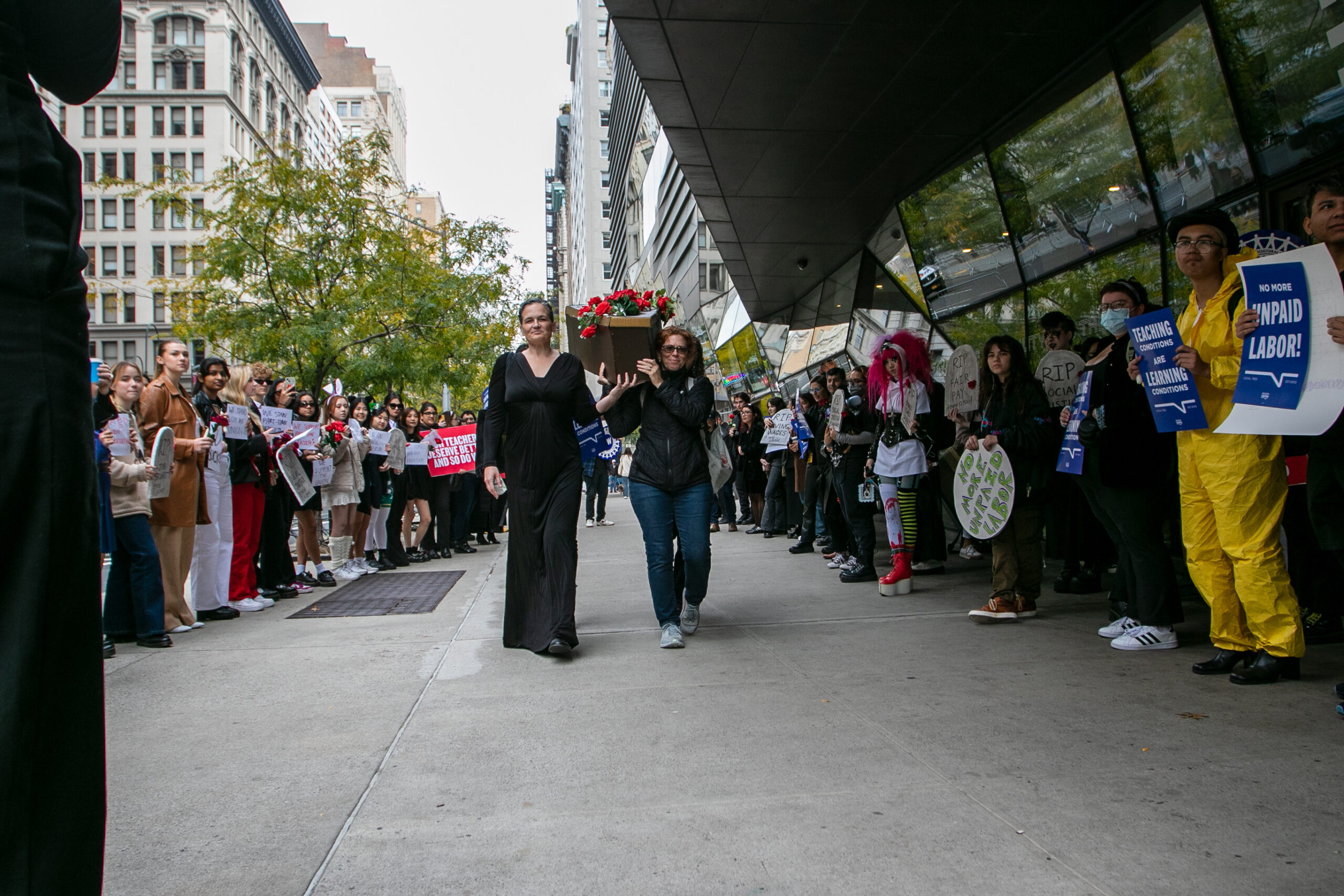 Union rep., Tamar Samir and professor Rachel Urkowitz march down Fifth Avenue holding a makeshift coffin covered in roses outside The New School's university center.