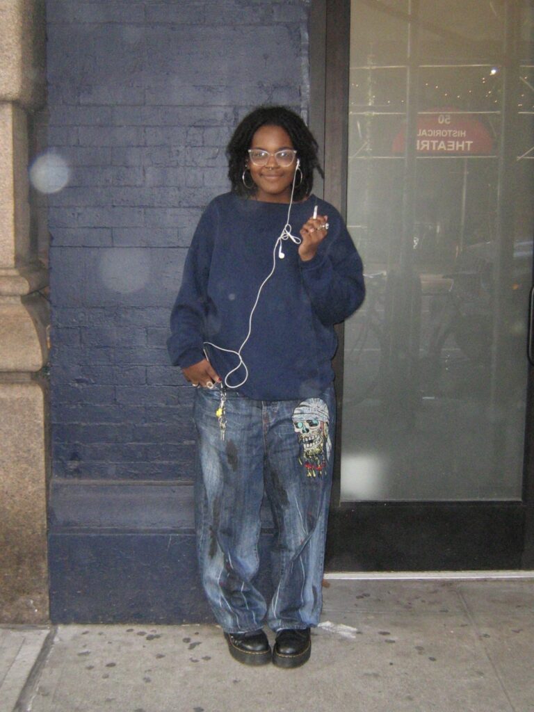 drama student in blue outfit smoking and listening to music.