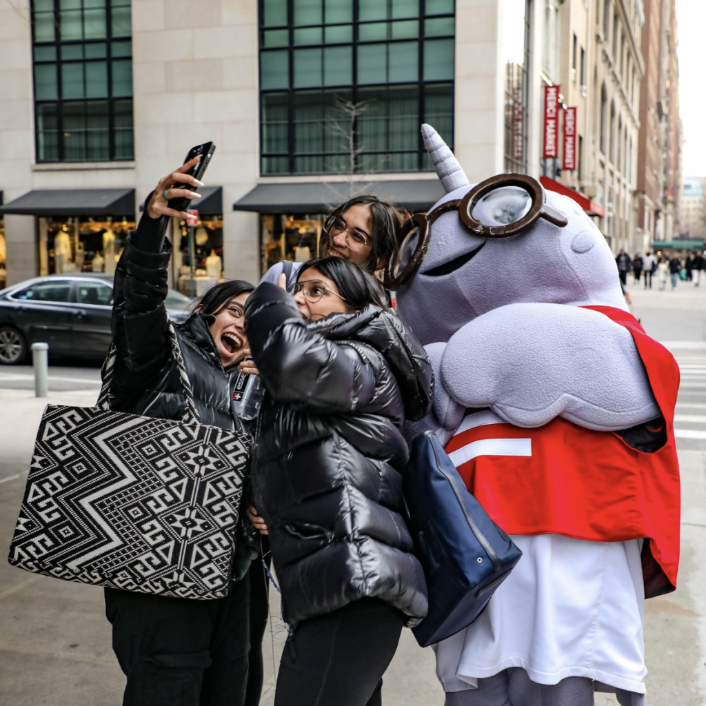 Image of three students posing with big smiles for a selfie with the Gnarls mascot.
