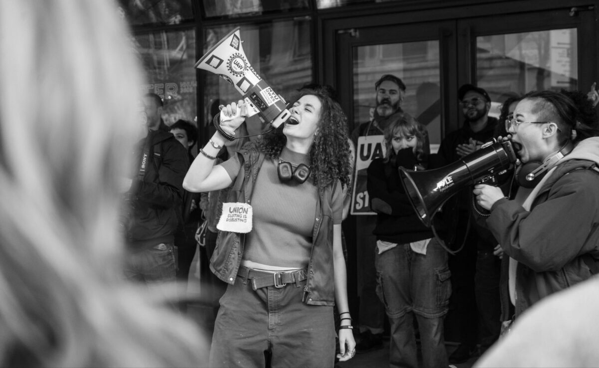 Protesters gather around two students with bullhorns in front of the University Center as they announce the occupation.