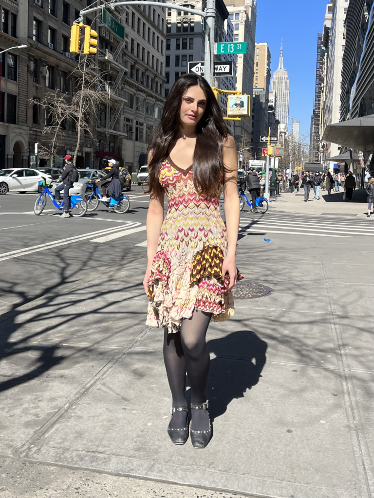 Second-year fashion design student Ariah Hamburg wears a multicolor dress with black tights and black heels while standing on the corner of Fifth Avenue and thirteenth street.