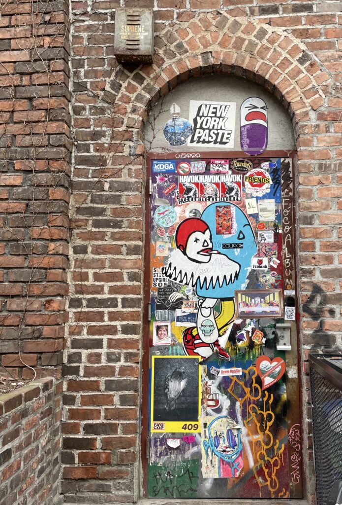 Brightly colored stickers collaged on a single doorway surrounded by brick. 