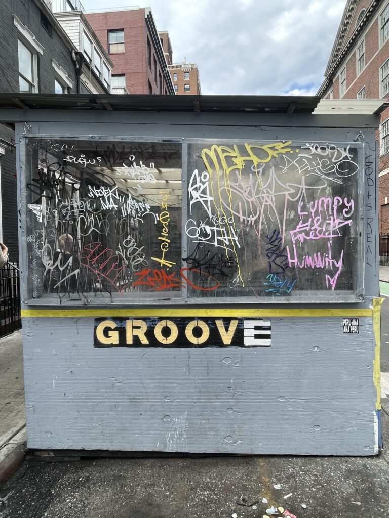 An outside seating booth at Groove Bar with a graffitied window. 