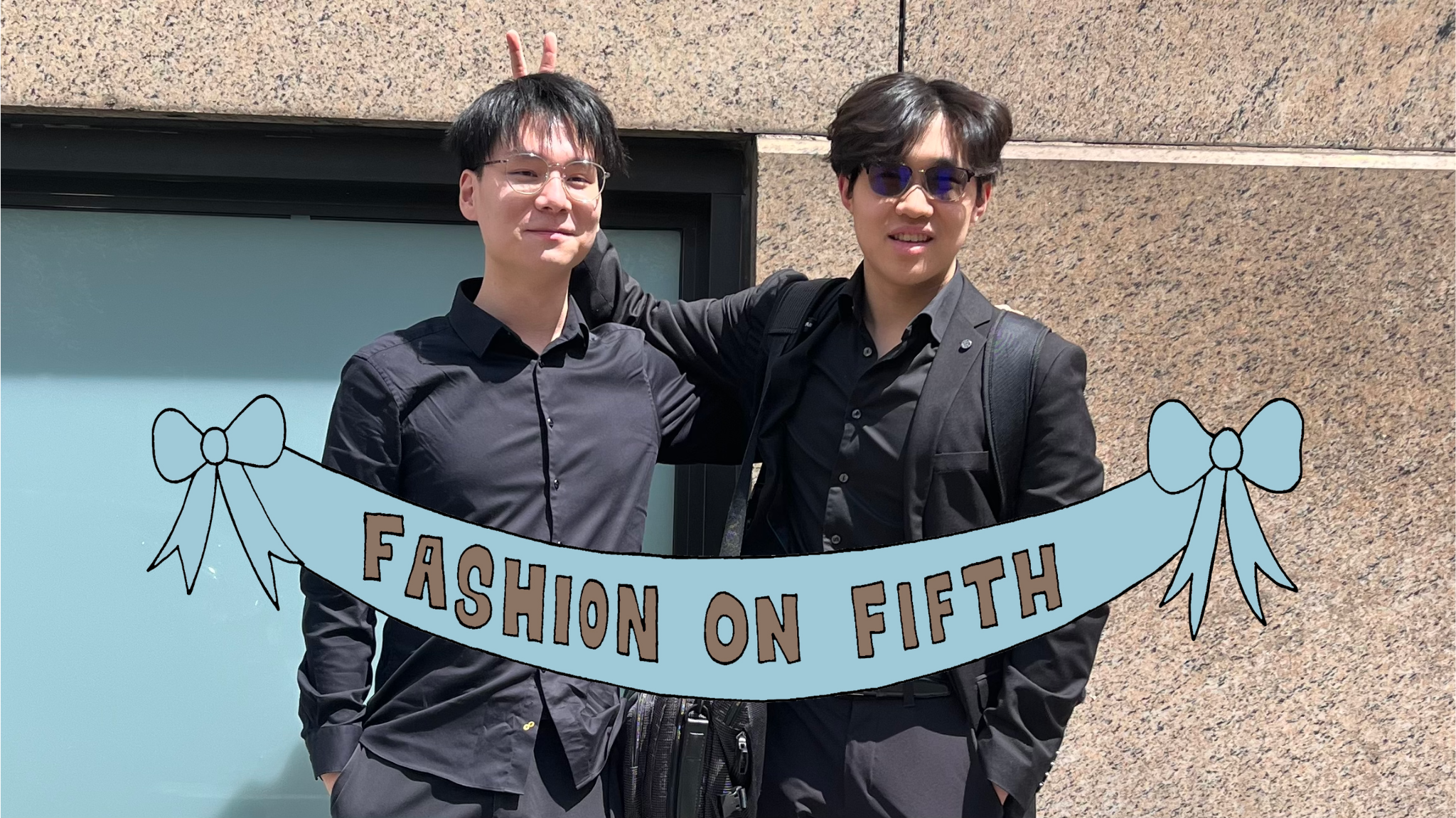 Two students stand next to each other in all-black outfits, one student makes peace sign bunny ears behind the other one’s head.