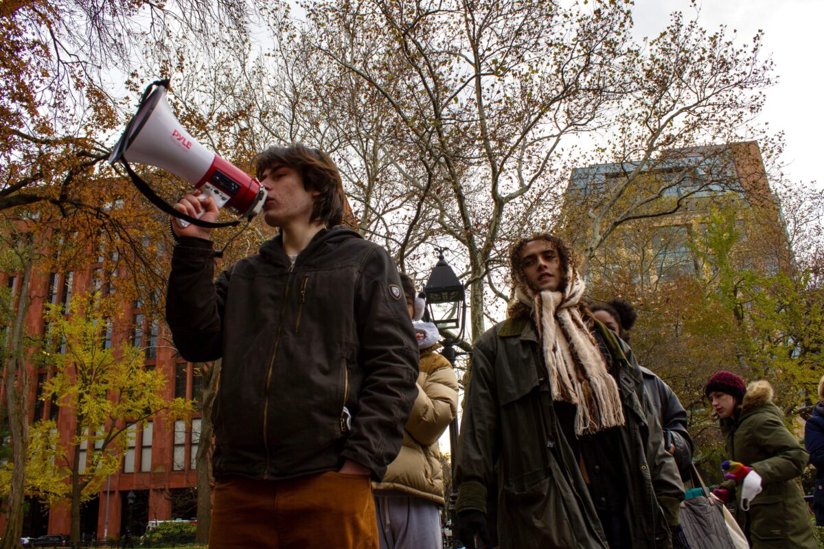 A man talks to a crowd through a megaphone while other members gather behind him.