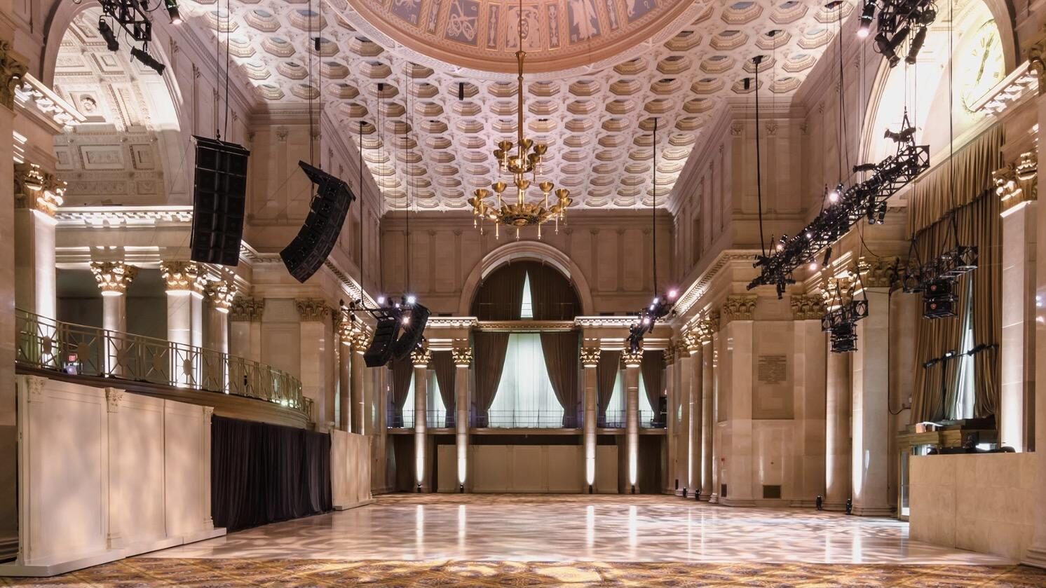 A large Ballroom with marble floors, a vaulted roof, and black blinds.