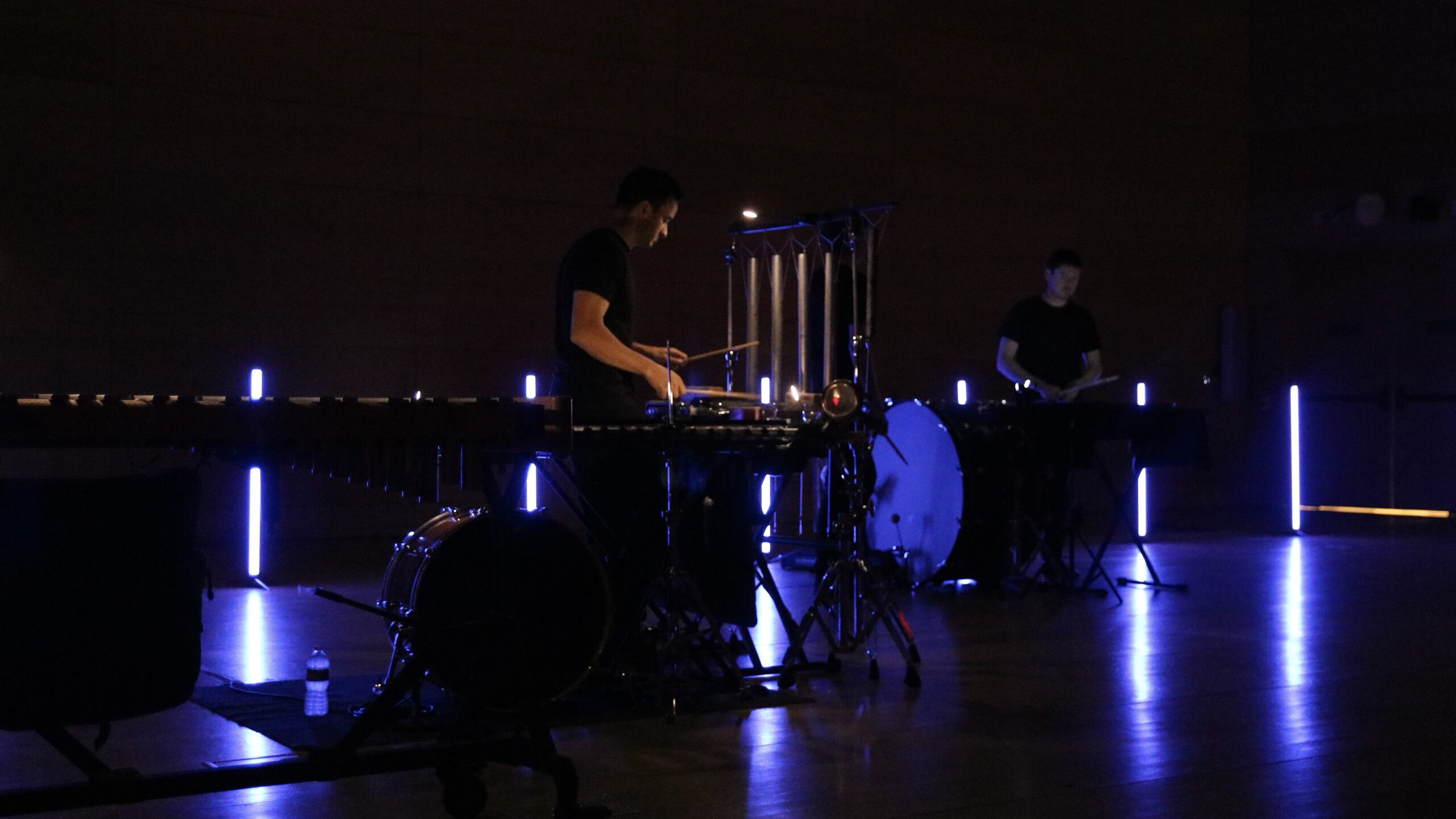 two members of the ensemble surrounded by blue lights as they play their instruments during Thursday night’s performance in the Tishman auditorium.