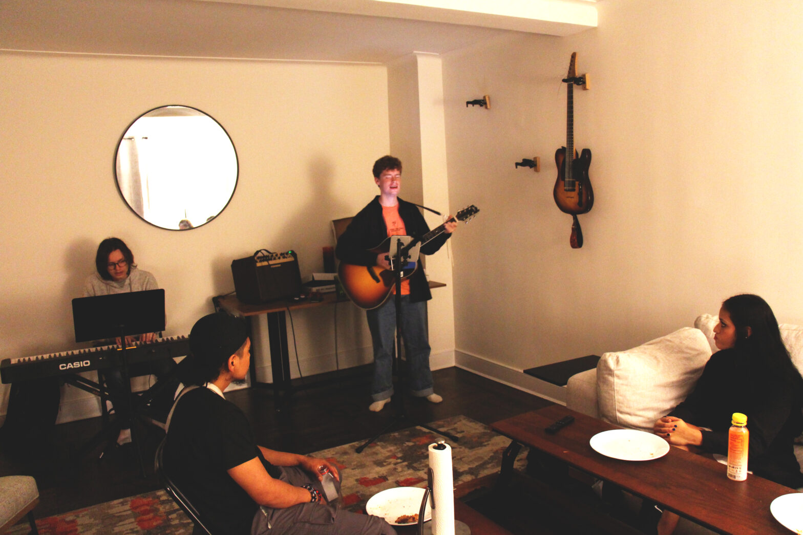 Four people playing music in a dimly lit living room.