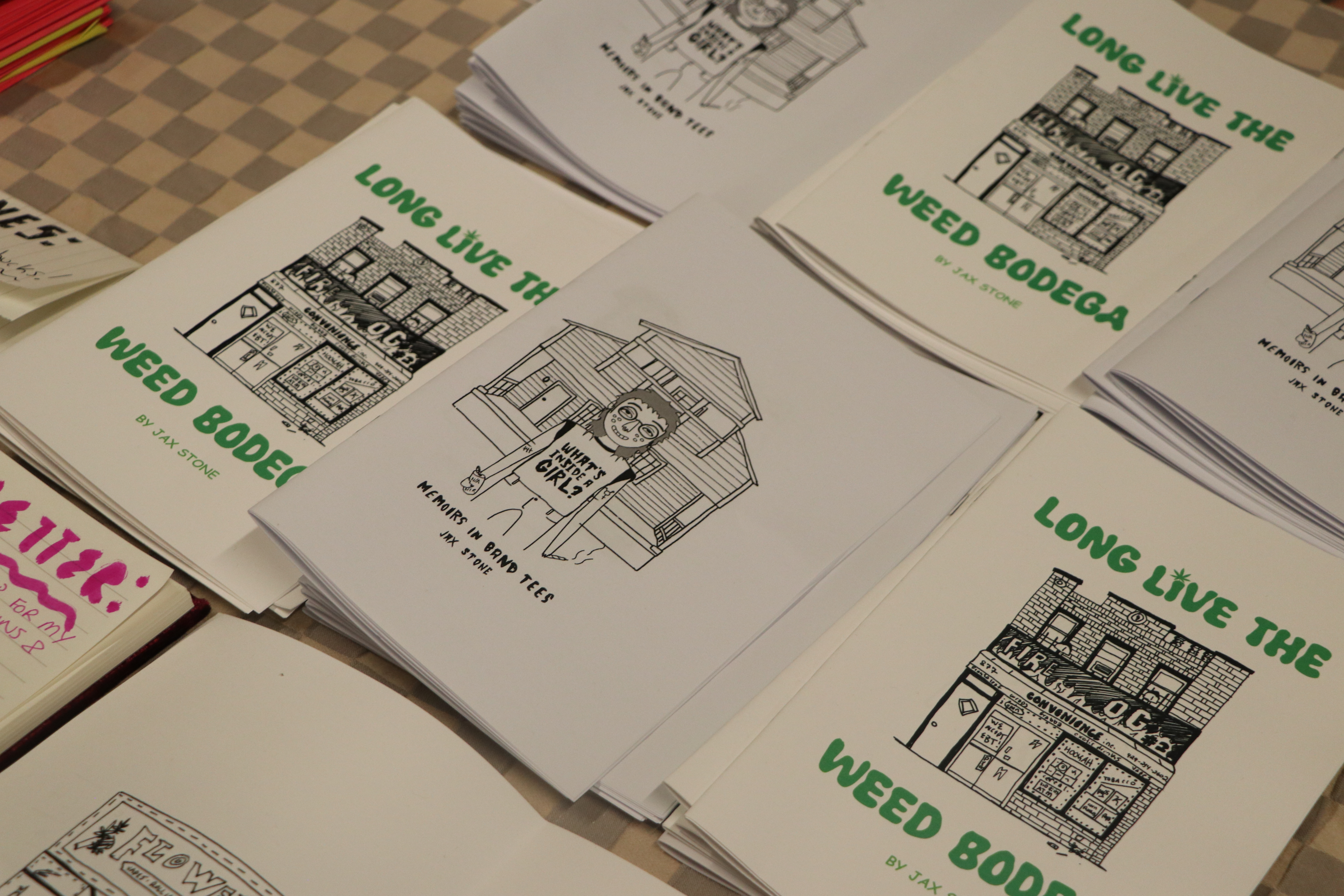 Zines titled "Long Live the Weed Bodega" lay out on a table. 