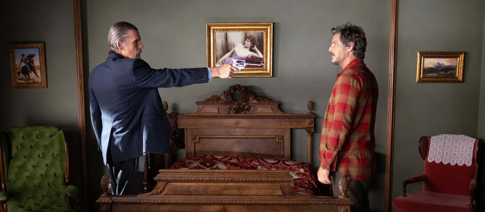 Ethan Hawke pointing a gun at Pedro Pascal in a rustic bedroom.