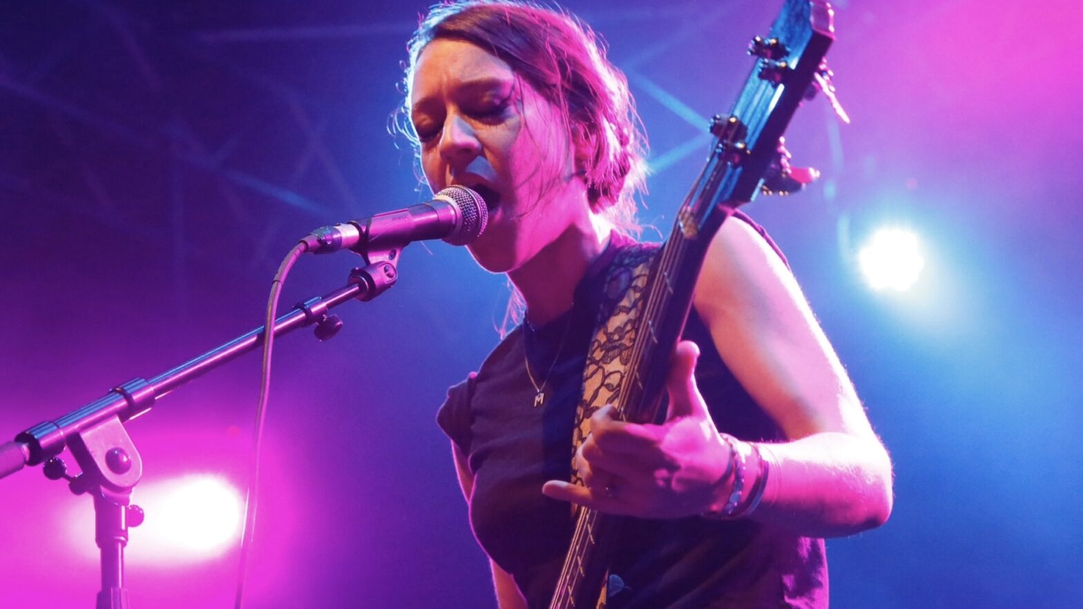 Solomon performing holding a guitar and singing into a microphone against a backdrop of blue and purple lights.