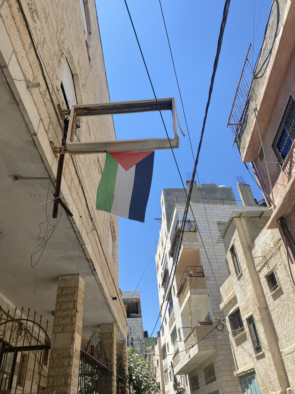 A Palestinian flag hangs from a broken store sign in Aida Refugee Camp, Bethlehem.