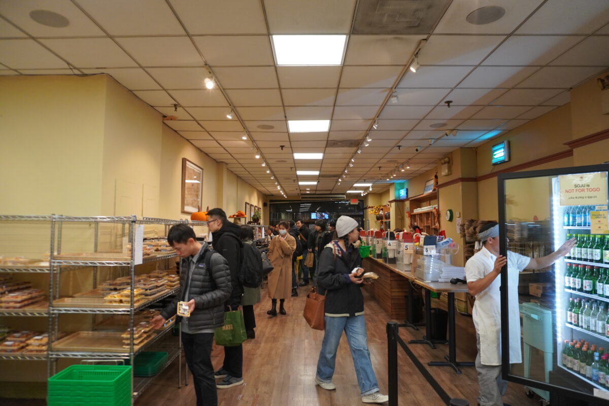 The inside of a restaurant where customers grab boxes of food from shelves.