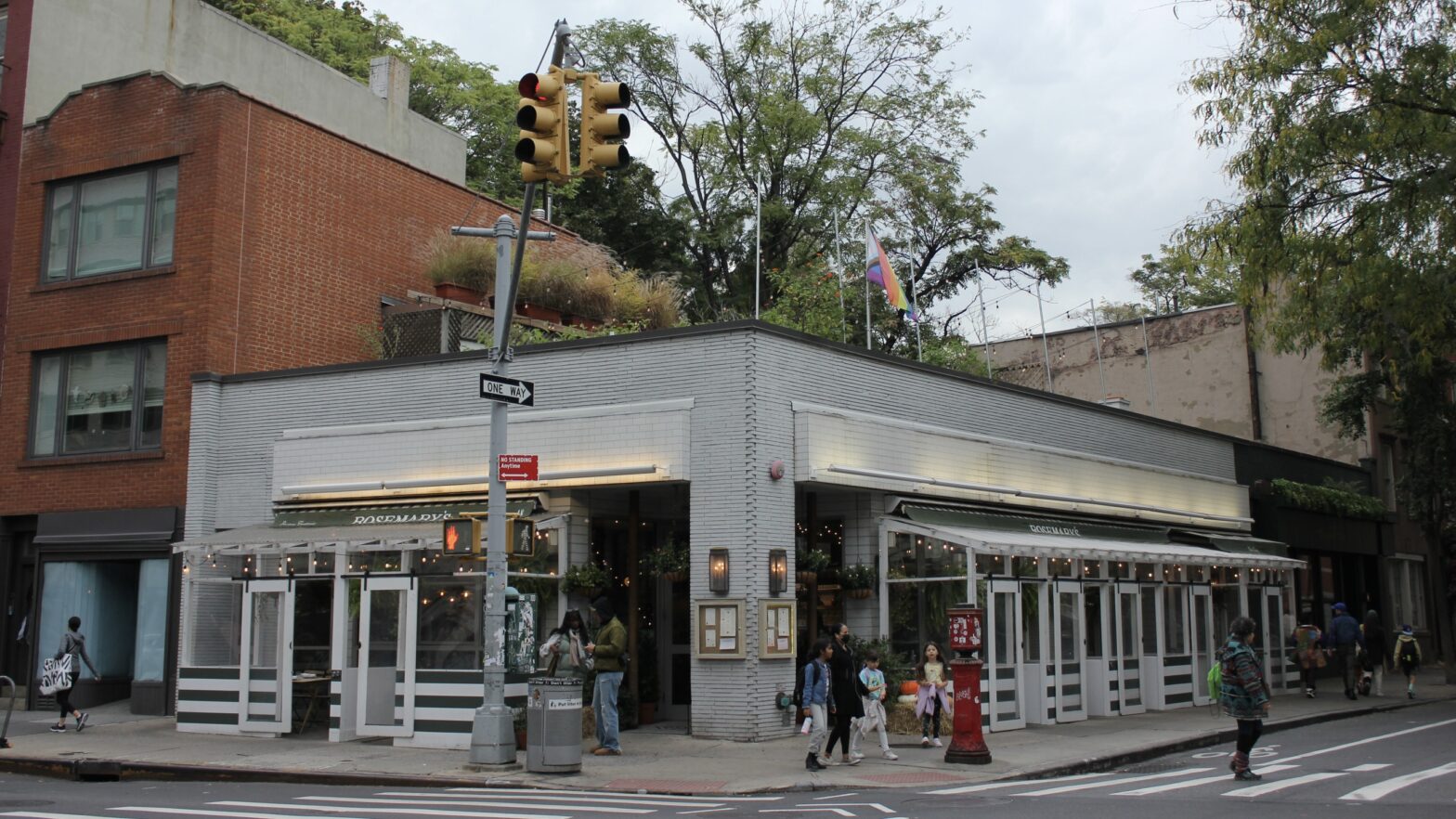 The outside of a corner restaurant with a garden on the roof.