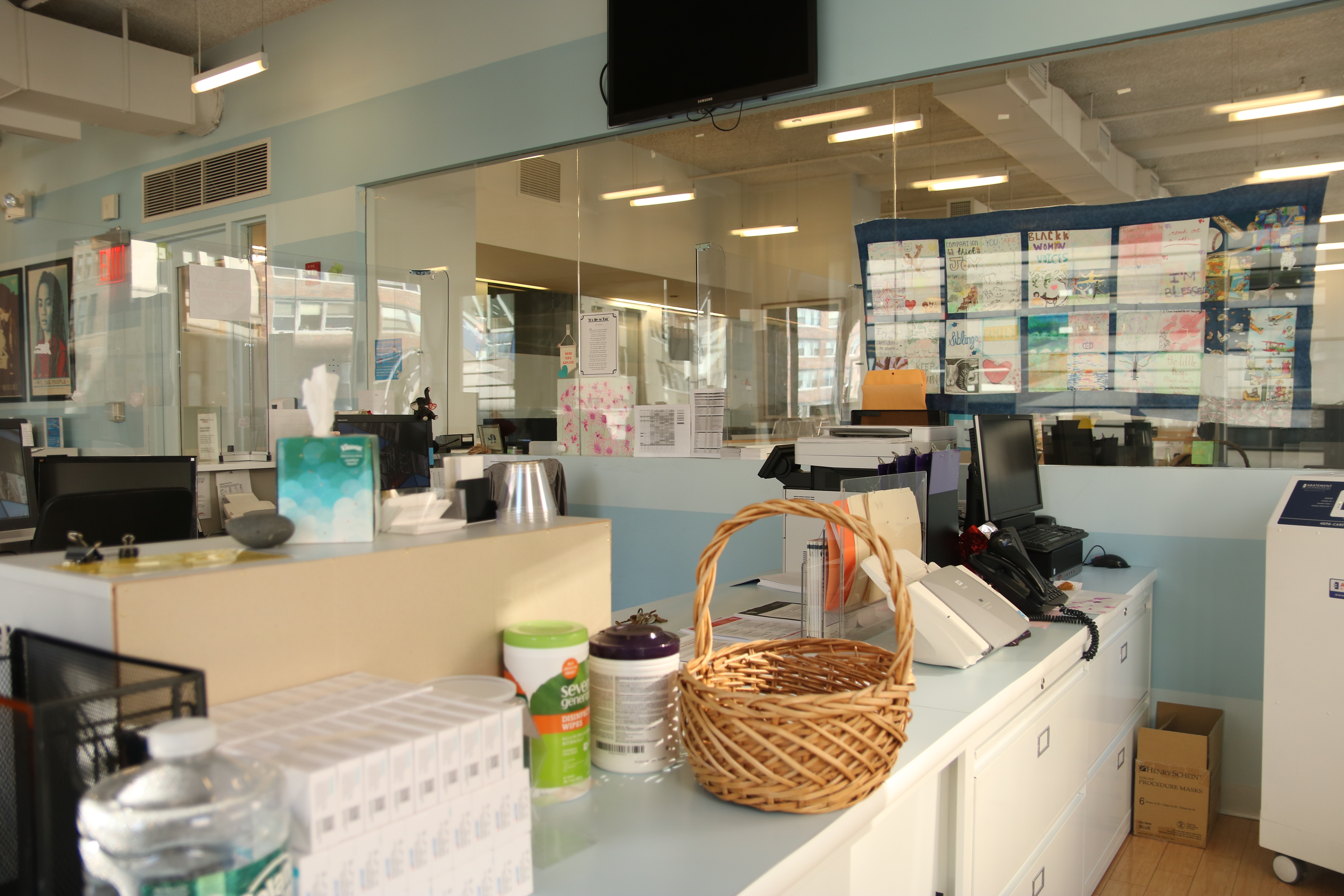 A medical front desk with a glass divider on the desk separating it in half.