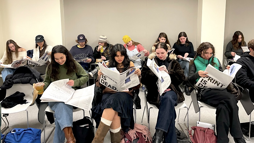 Free Press reporters sitting in a classroom reading the print newspaper