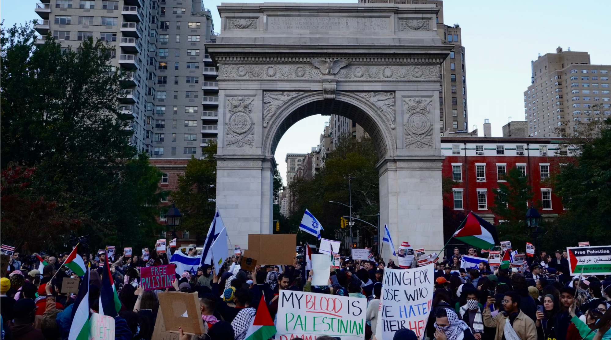 Israeli flags and Palestinian protest signs held up under the Washington Square Arch
