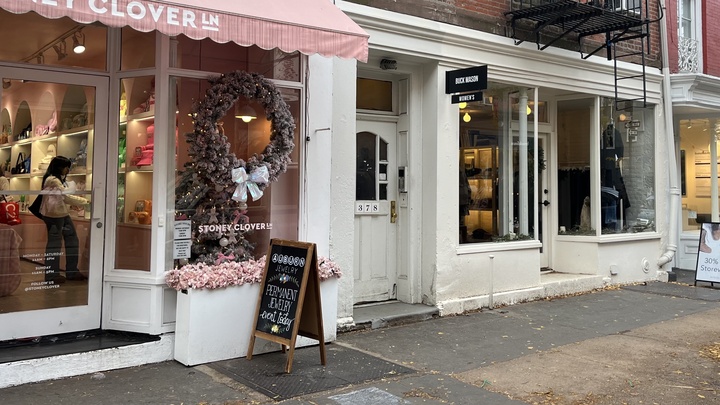 White and pink retail storefronts on Fifth Avenue decorated with wreaths and bows for the holidays.