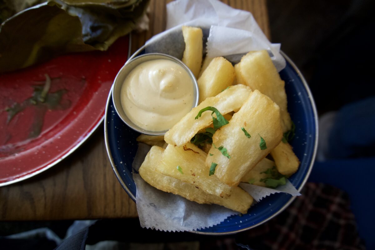 A bowl with yucca fries and dipping sauce.