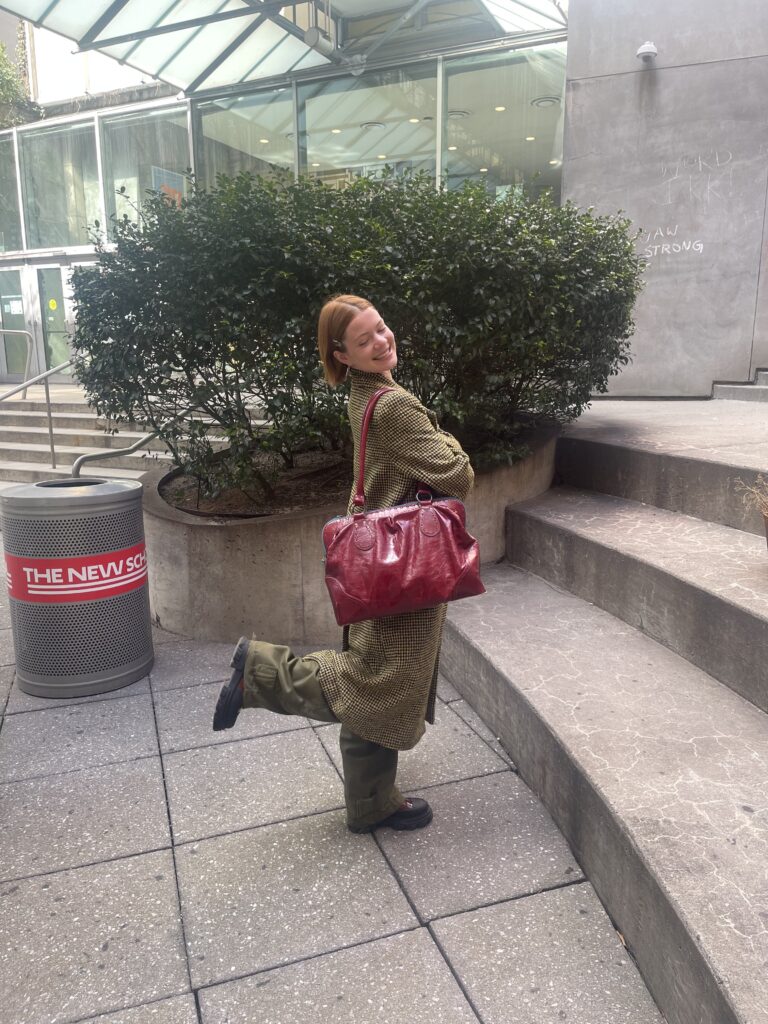 Jane is posing with a vintage red patent leather John Fluevog purse, in the middle of the Lang Courtyard.