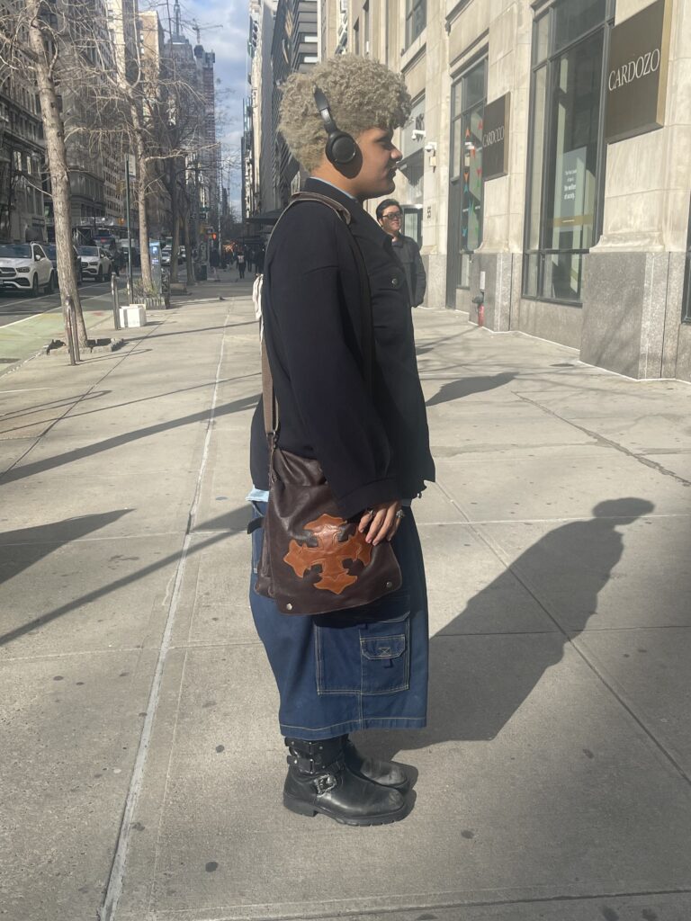 Dakota posing with a brown side bag with a light brown cross on it.