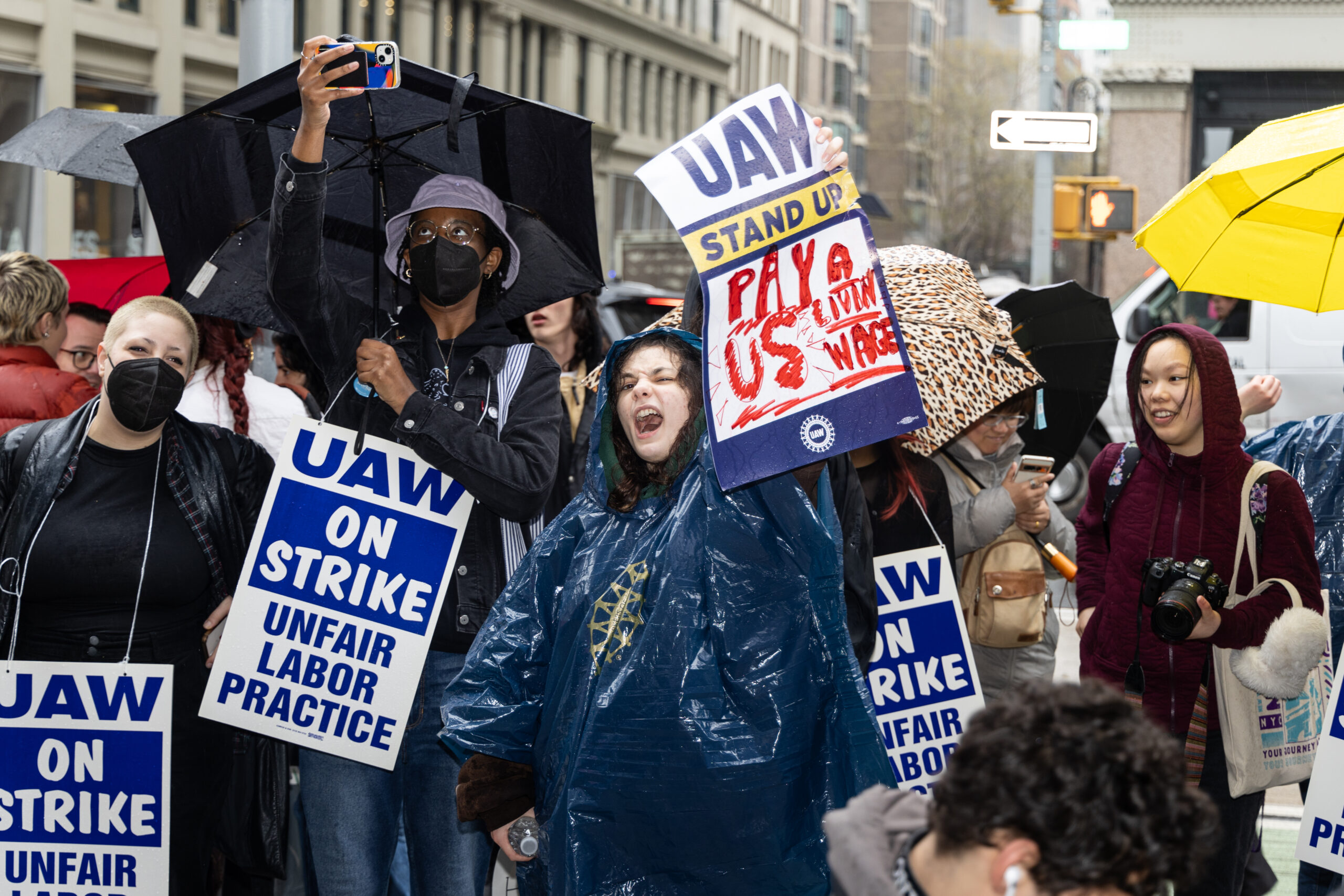 Image of picketers holding signs. The signs read “UAW on strike. Unfair Labor Practice."