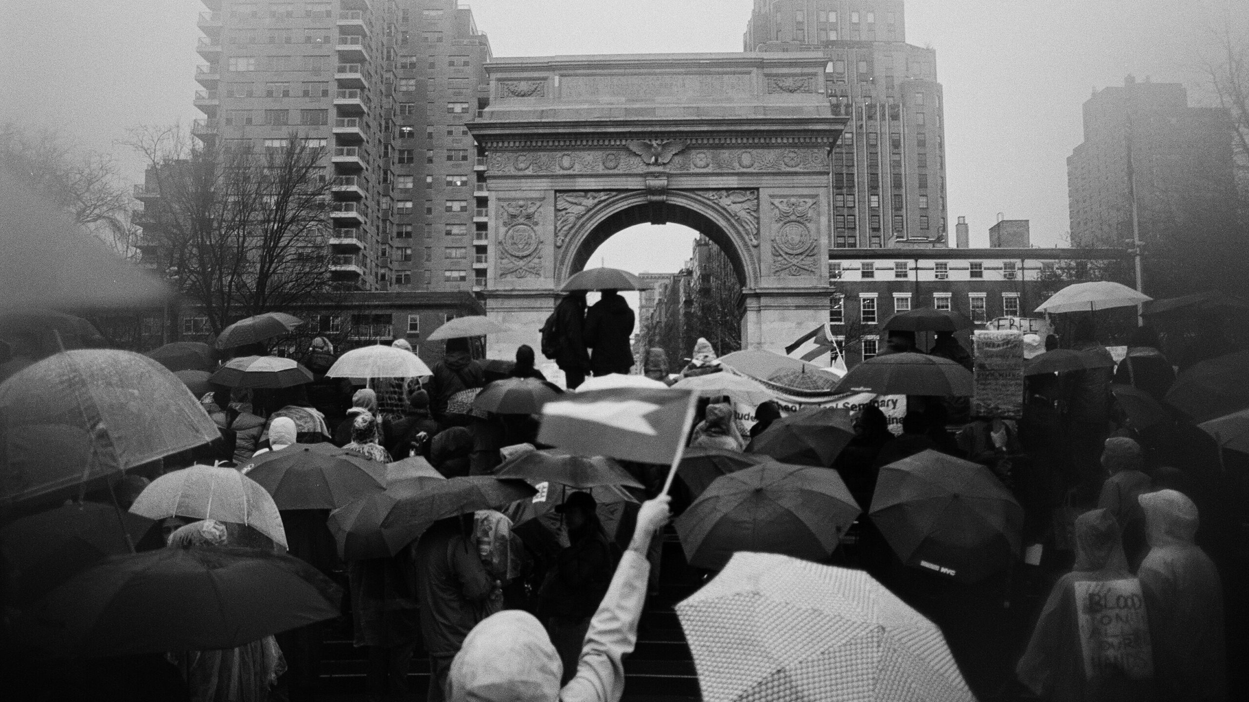 black and white image of umbrellas under Washington Square Arch.