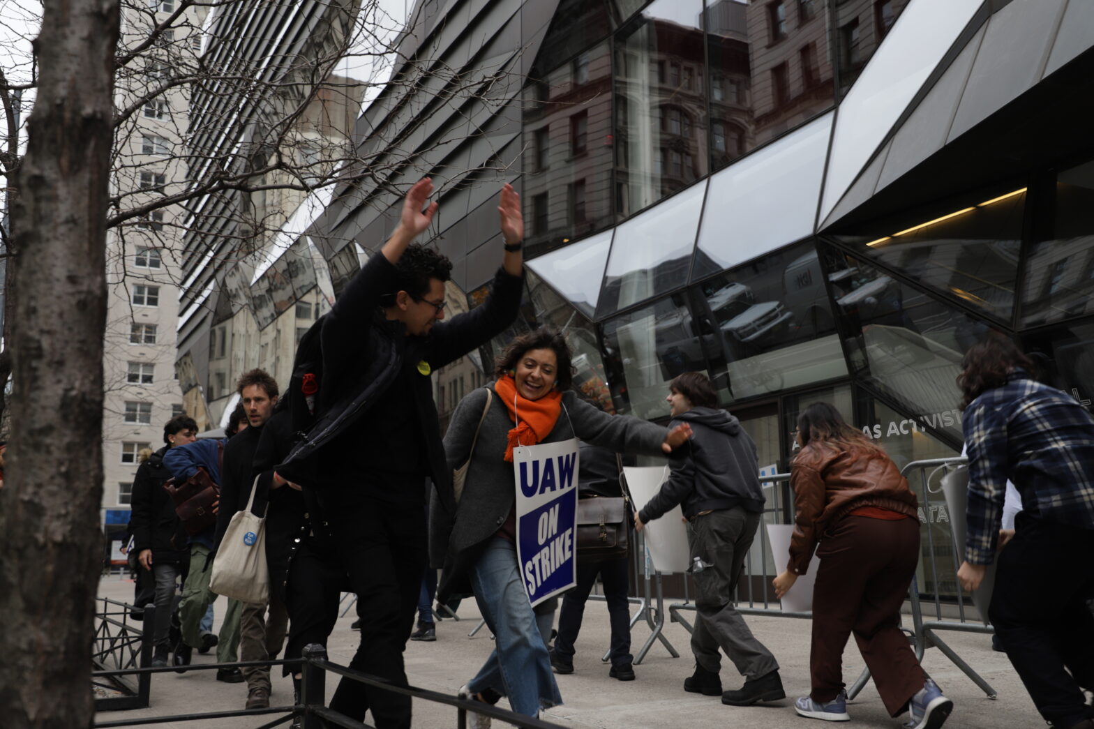 Alt text: Image of a woman and a man laughing as they walk the picket line.