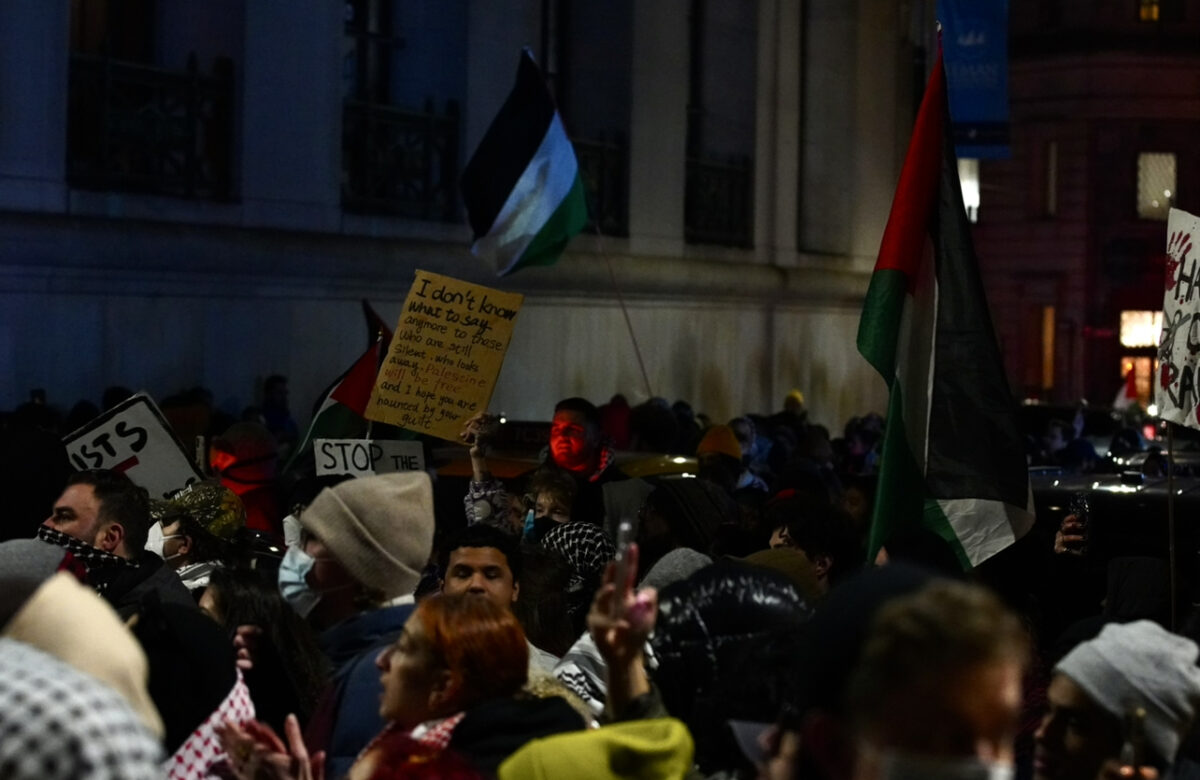 Crowd of protesters in motion with a mans face in the center illuminated red 