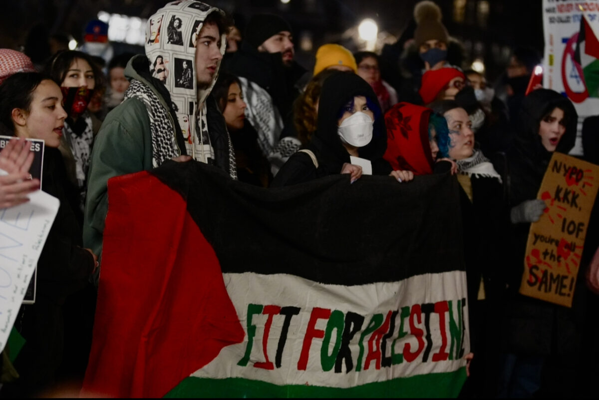 A group the students hold a Palestinian flag that reads “FIT for Palestine” in the middle