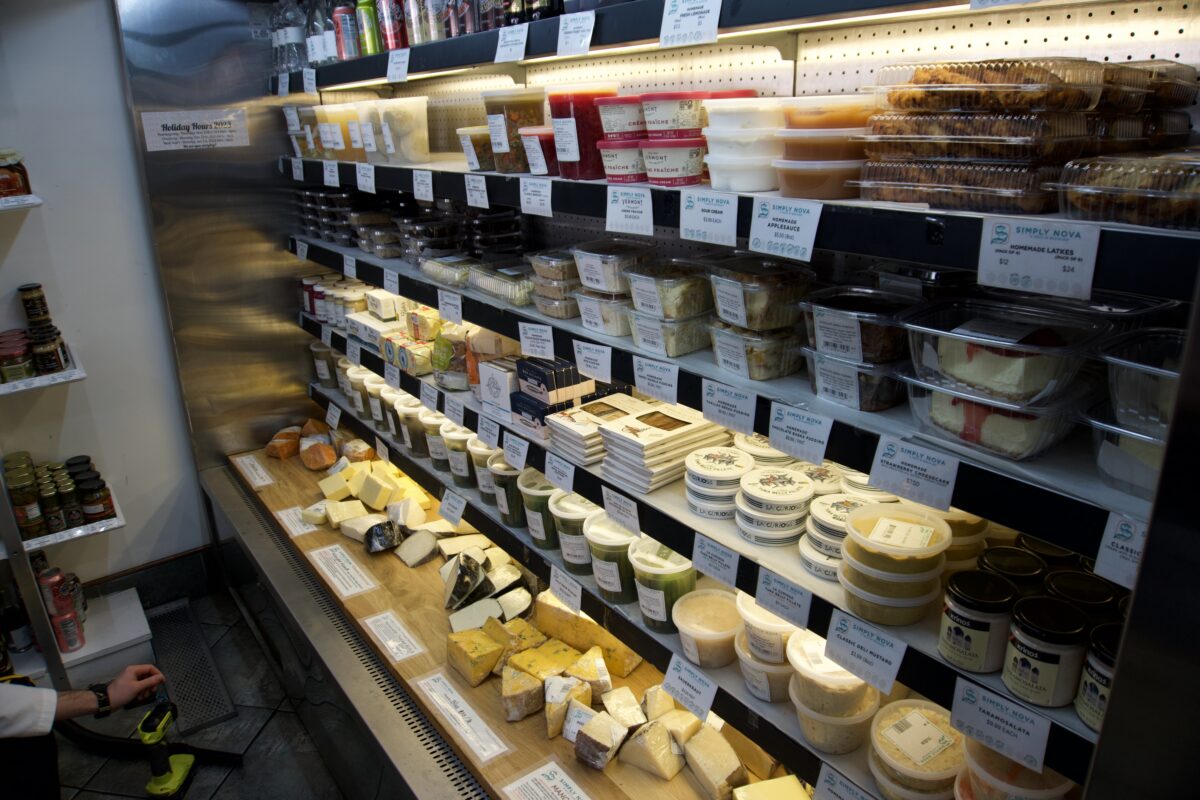An open fridge filled with containers of food and cheese.
