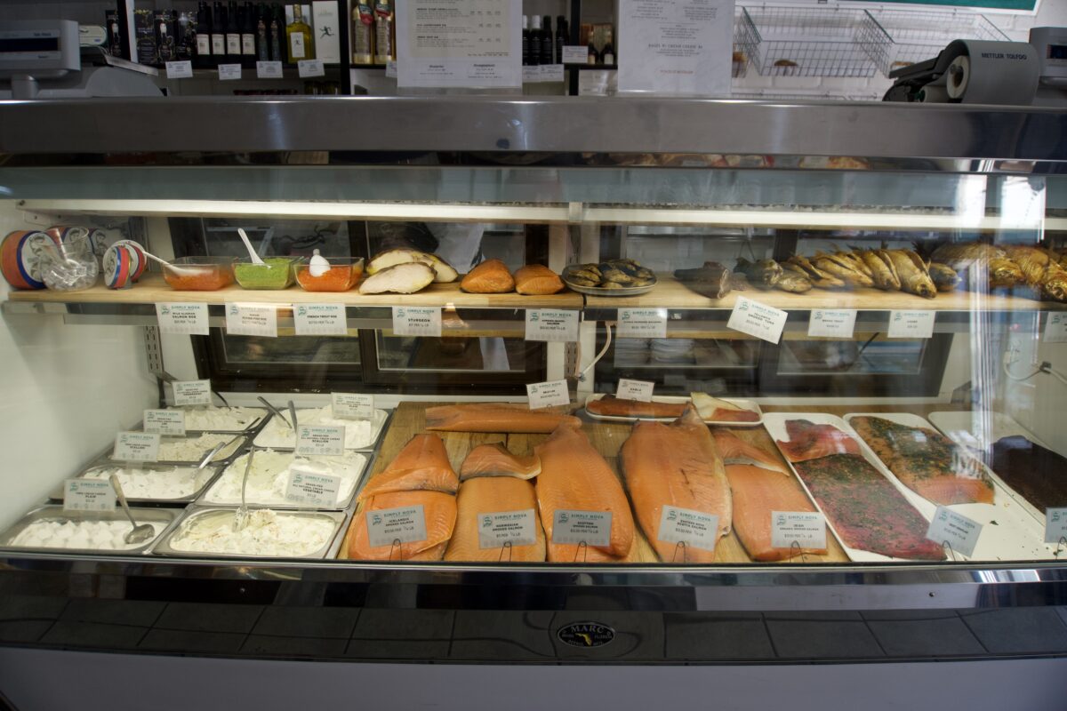 A lit up display case filled with smoked fish and cream cheese.