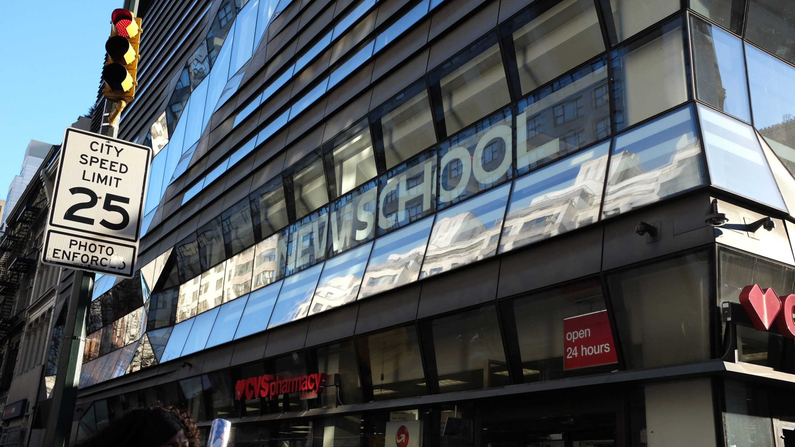The front of a building with "The New School" spelled out and a speed limit sign in the corner.
