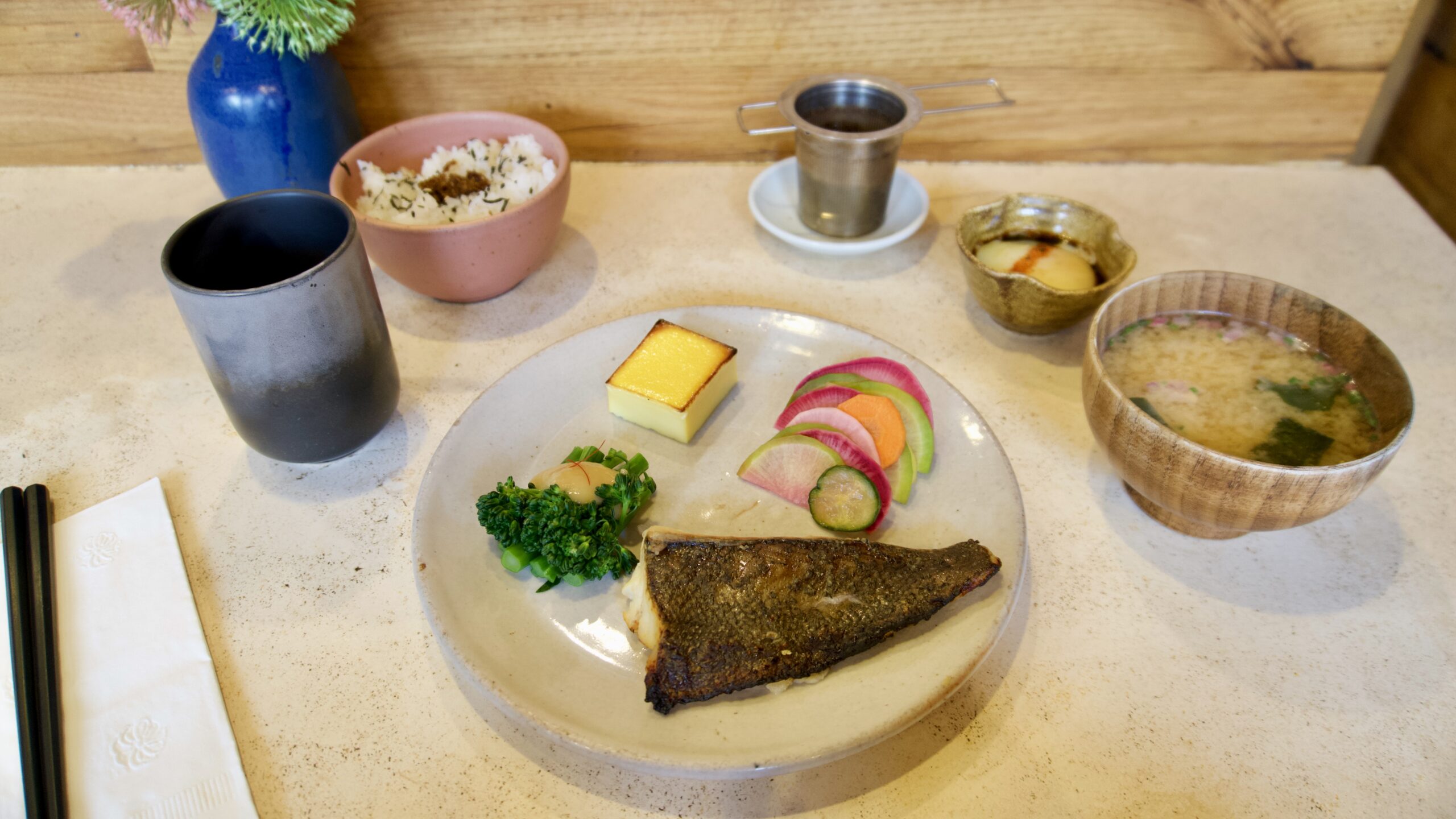 A Japanese breakfast set with fish, vegetables, soup, rice and egg.