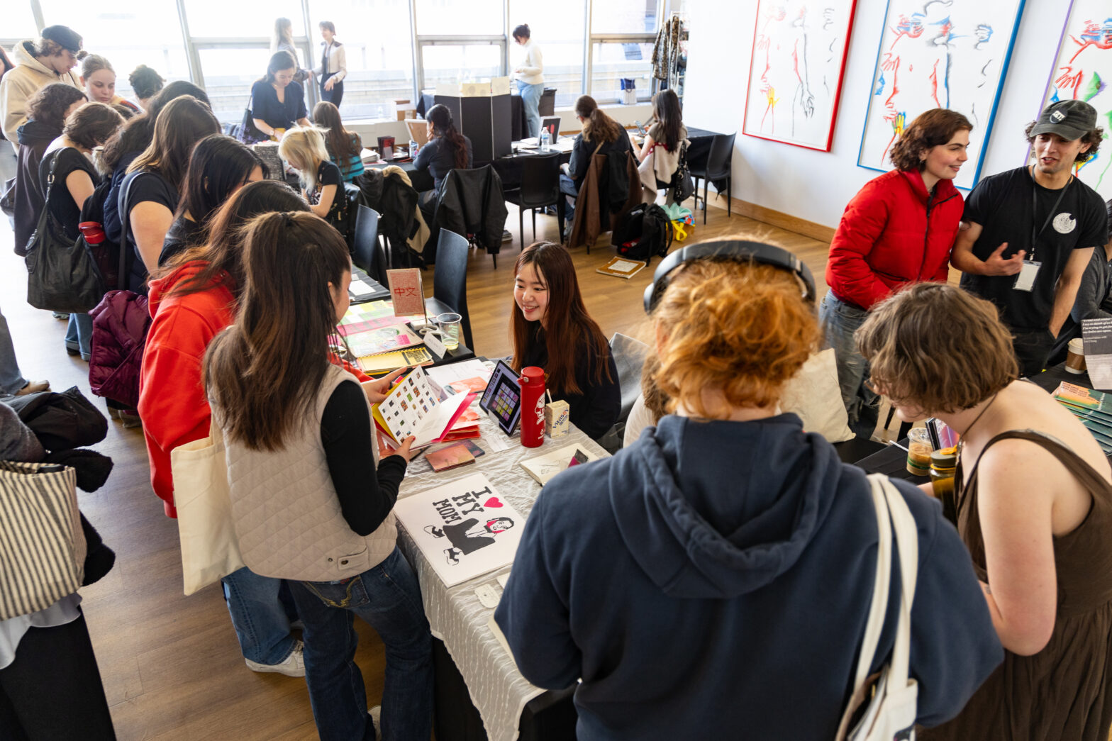 Tables crowded with students looking at student work and talking with exhibitors.